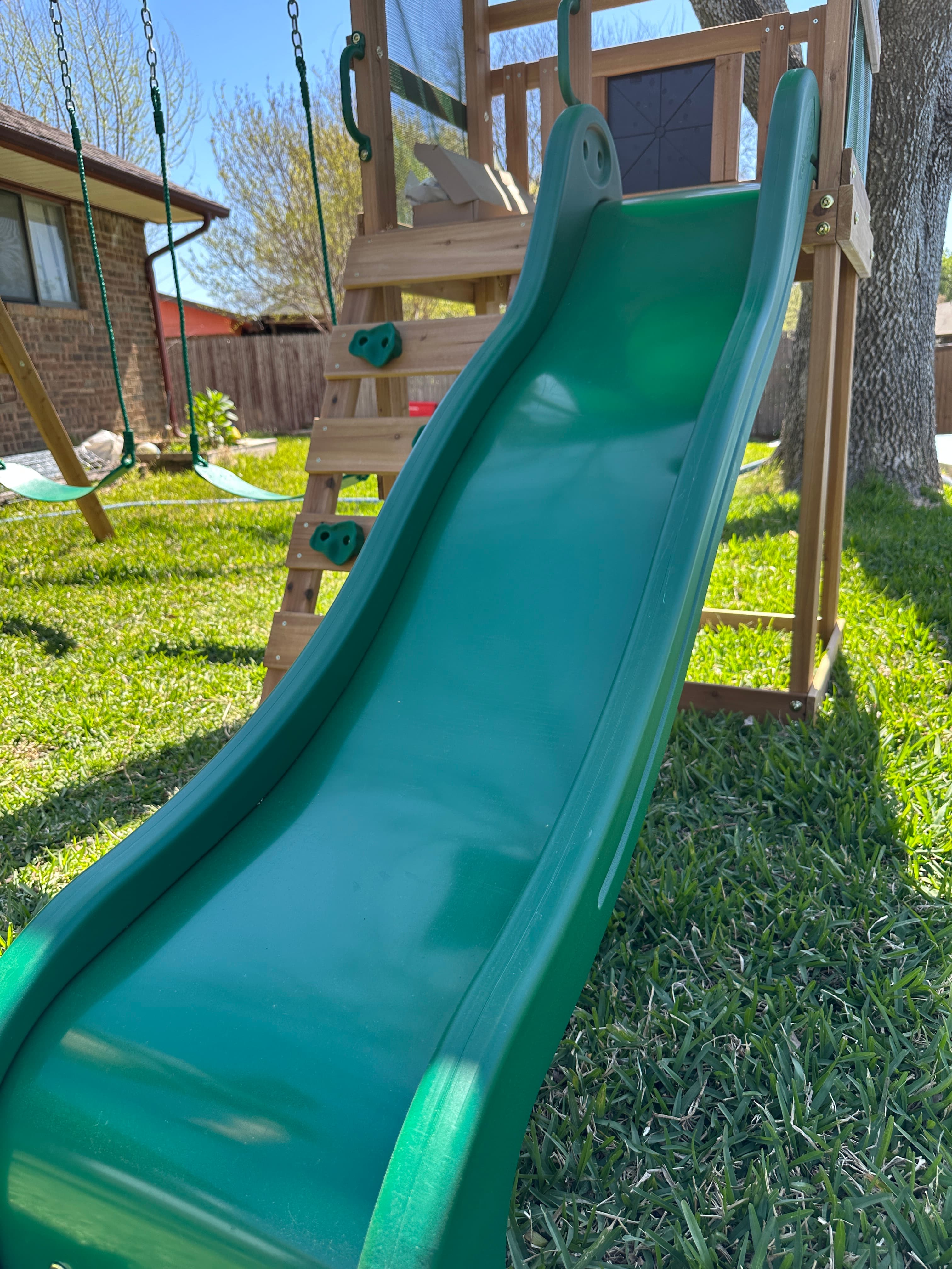 Large green slide integrated into wooden structure