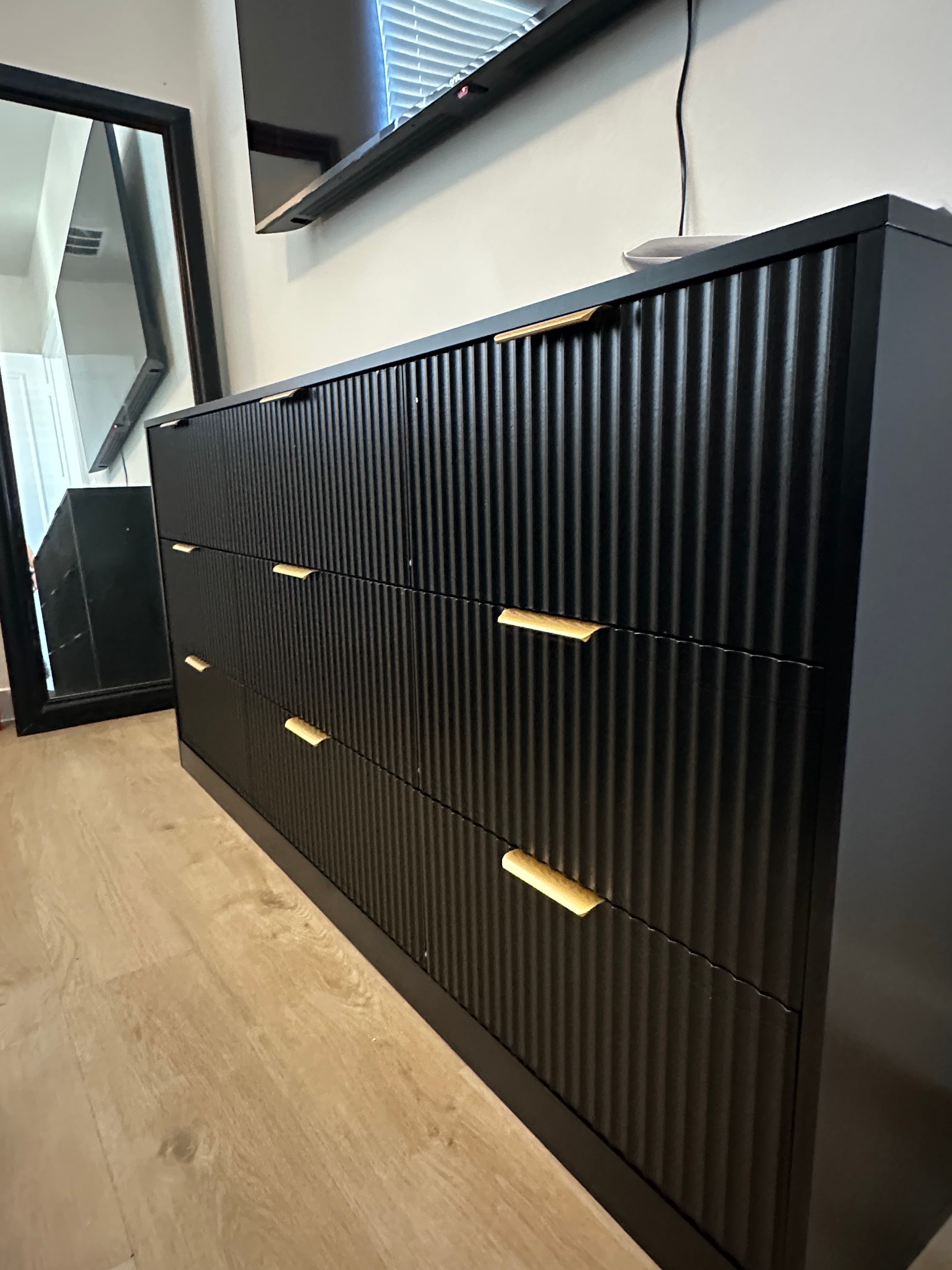 Large black wardrobe with slatted doors and brass handles